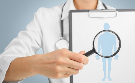 Unrecognizable doctor is showing clipboard with silhouette of a man under the medical magnifying glass