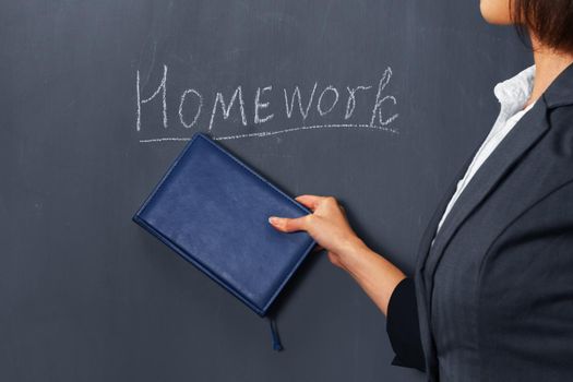 Unrecognizable female teacher indicates by book on homework