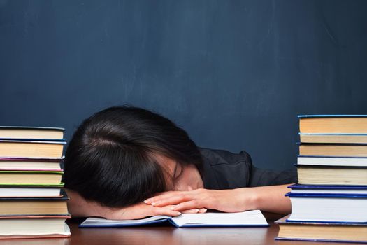 Tired woman lies between stacks of books