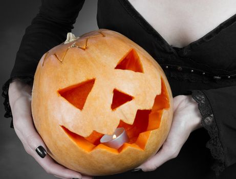 Carved Halloween pumpkin in the hands of woman