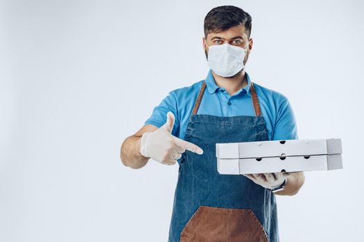 Pizza delivery man in medical gloves and mask against grey background. Safe service while coronavirus covid-19 outbreak