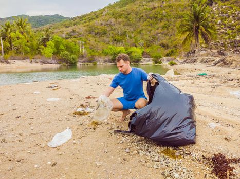 Man in gloves pick up plastic bags that pollute sea. Problem of spilled rubbish trash garbage on the beach sand caused by man-made pollution and environmental, campaign to clean volunteer in concept.