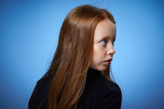 redhead girl with freckles on her face posing close-up blue background. High quality photo