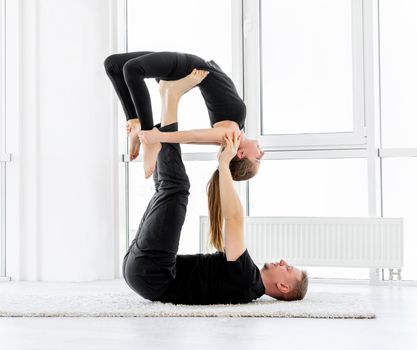 Couple doing paired gymnastic exercises at home