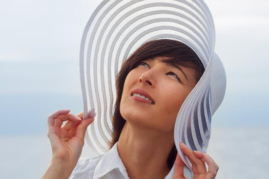 Beautiful young woman in a hat with a wide brim at sea