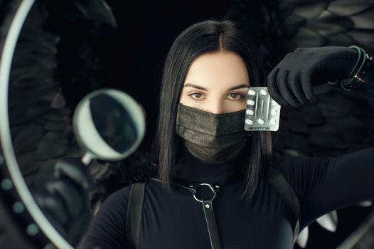brunette wearing a protective black coronavirus mask with pills and a magnifying glass