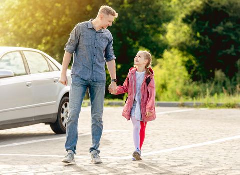 Little girl going back to school holding hands with father