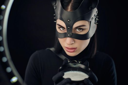 the woman in a black body belt and cat mask with a bowl of milk