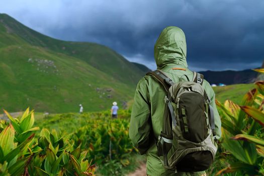 Hiker man walks along a mountain path with a backpack.