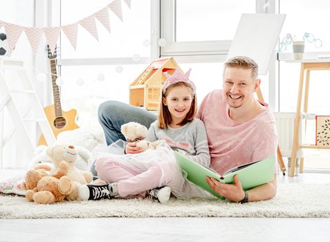 Cute little daughter with happy father reading book