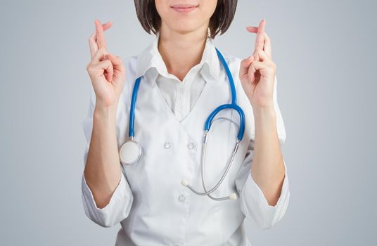 Female doctor crossed her fingers on a blue background