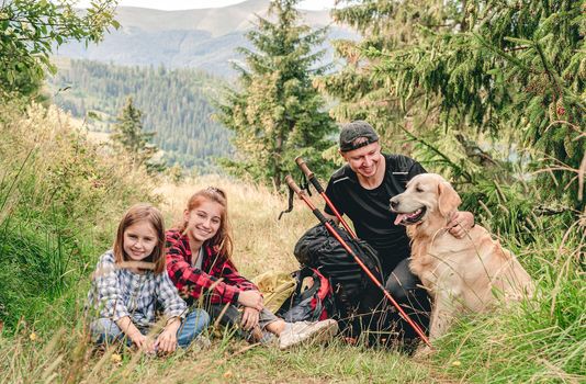 Smiling sisters with father resting during mountain hiking