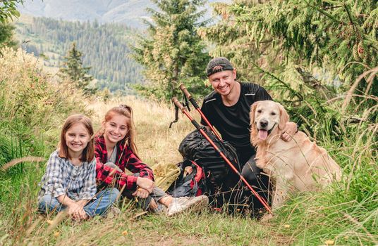 Smiling sisters with father resting during mountain hiking