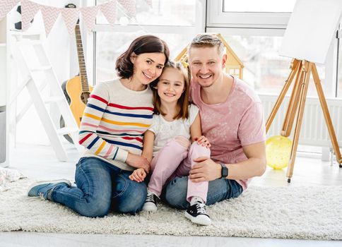 Happy family sitting together on floor in light room