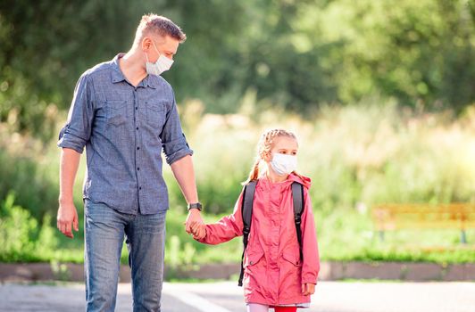 School girl with father in medical masks going back to school