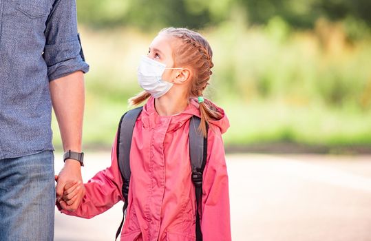 School girl with father in medical masks going back to school