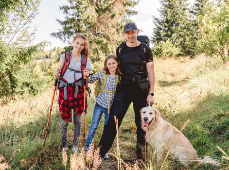 Smiling father with daughters and dog hiking sunny mountain