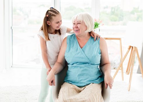 Smiling grandmother with cute granddaughter at home