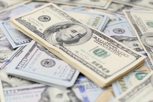 A stack of money. Heap of one hundred dollar bills on money background. Fake money. Shallow depth of field. Selective focus.