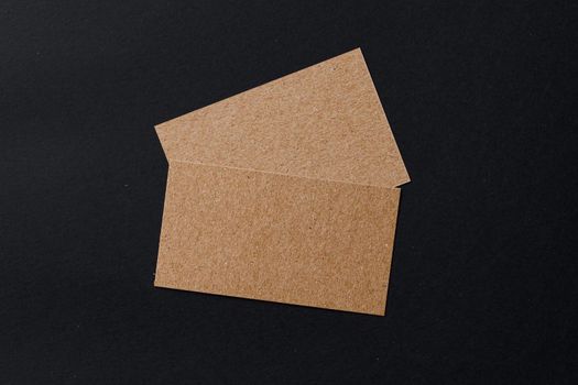 Business card of a craft paper on black background, top view