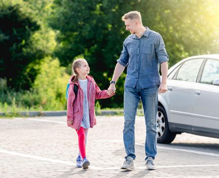 Little girl going back to school holding hands with father