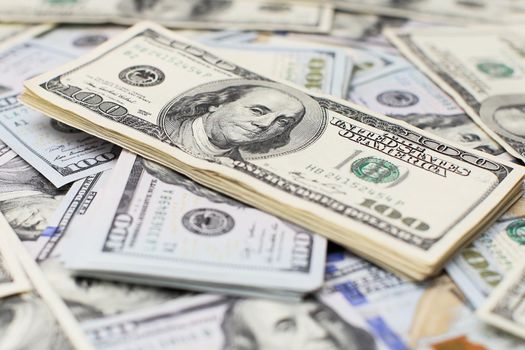 A stack of money. Heap of one hundred dollar bills on money background. Fake money. Shallow depth of field. Selective focus.