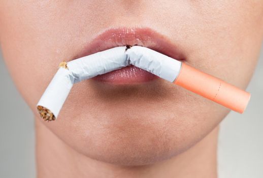 Female lips holding a broken cigarette, close-up