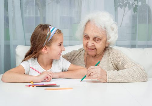 portrait of little girl with grandmother drawing with pencils