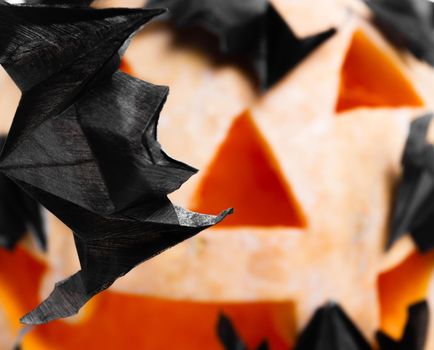 Origami bats handmade on the halloween pumpkin background. Close-up