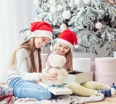 Smiling sisters in santa hats taking opened gifts