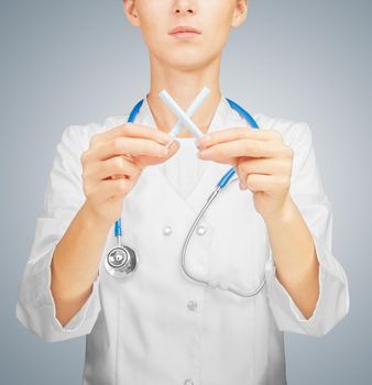 Doctor holds crossed cigarettes, concept of healthy life