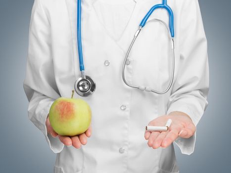 Unrecognizable doctor offers a choice an apple or a cigarette