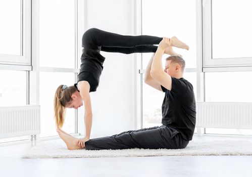 Cute girl and sporty dad making acrobatics indoors