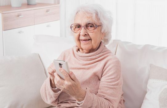 Smiling great-grandmother talking by smartphone