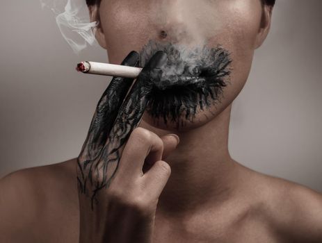 A woman smokes a cigarette, her hand and her mouth blackened, concept of a slow death from smoking