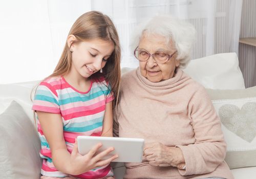 Granddaughter showing great-grandmother something on tablet
