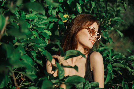 smiling woman wearing sunglasses green leaves nature fashion. High quality photo