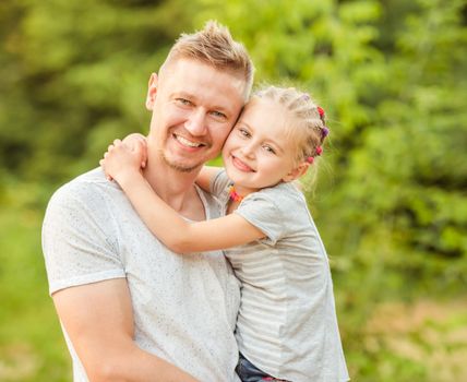 Happy dad holding smiling little daughter hugging