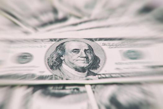 A stack of money. Heap of one hundred dollar bills on money background. Fake money. Shallow depth of field. Selective focus.