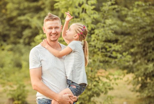 Happy dad holding little blond daughter