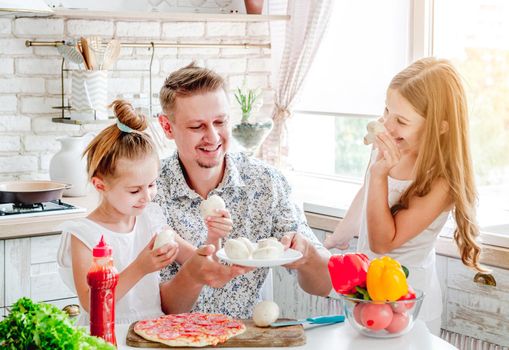 dad with two little daughters preparing pizza in the kitchen