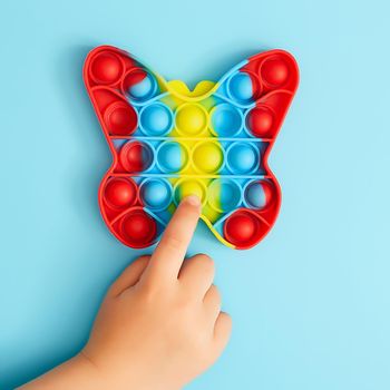 Trendy toy antistress. Anonymous child with colorful poppit game. Image of trendy Pop it fidget toy . Top view of the new sensory toy