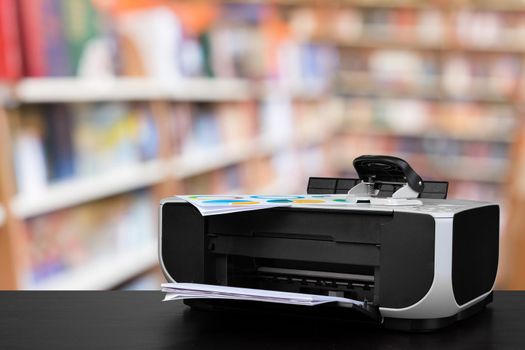 Compact laser printer on black desk against blurred background, close up