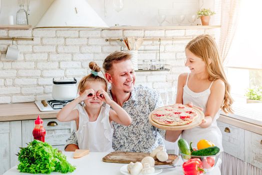 dad with two little daughters preparing pizza in the kitchen