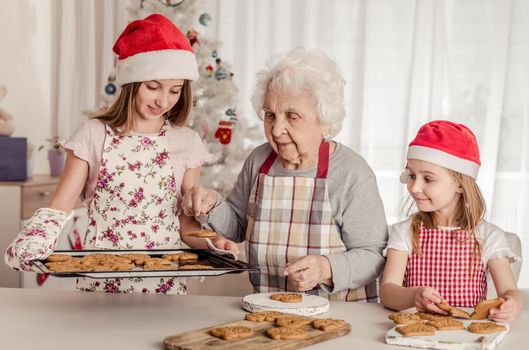 Grandmother with granddaughters in santa hats baking cookies