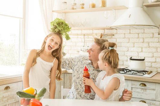 dad with two little daughters have a fun in the kitchen