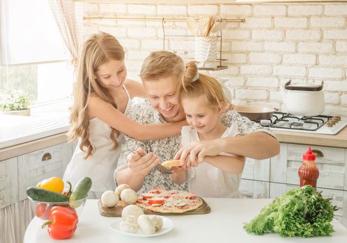 dad with two little daughters preparing pizza in the kitchen