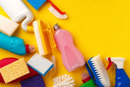 Set of cleaning supplies on yellow color background, top view