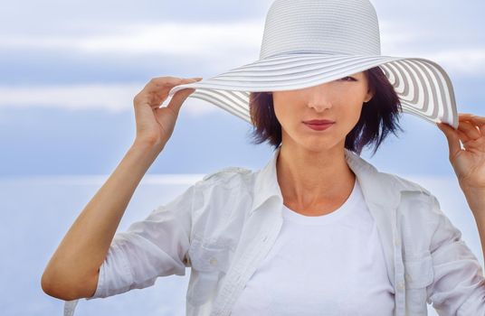 Fashionable woman in a hat on a background of the sea