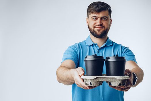 Man coffee shop worker giving takeaway cups of coffee on light grey background